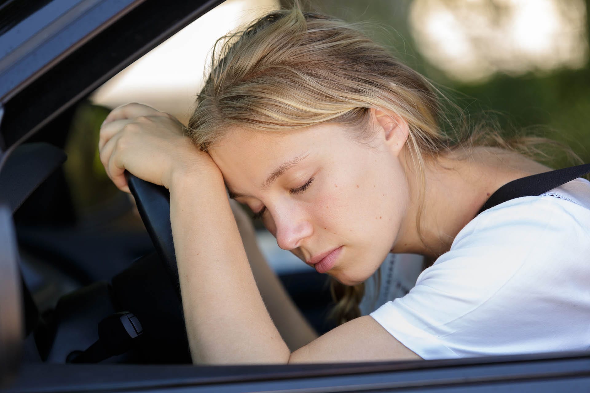 Tired woman asleep in her car due to sleep apnea