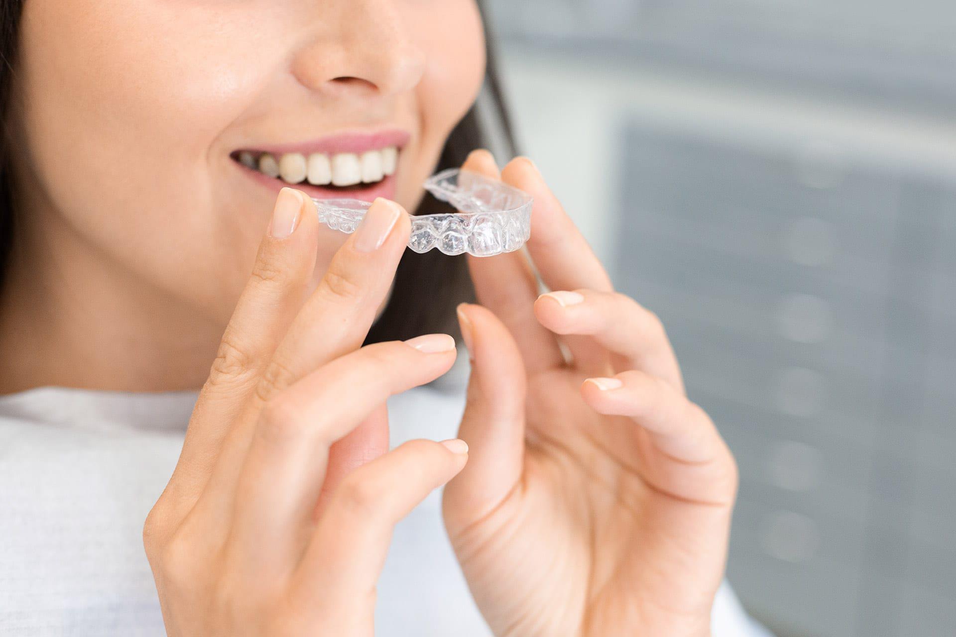 Woman in inserts an Invisalign clear orthodontic aligner from best dentist El Dorado Hills CA
