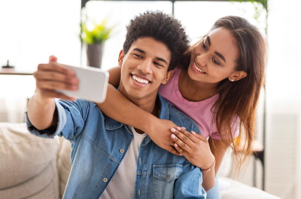 Happy young couple takes selfie to show off new smiles from best dentist Arden-Arcade CA