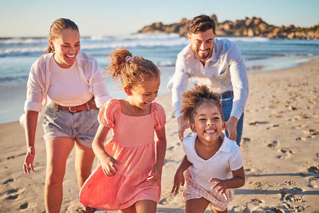 Folsom family with young children running on the beach with huge smiles after getting non-invasive ozone treatment from Digiorno Dental Fitness.